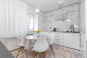 a white kitchen with a table and white chairs at Просторная квартира со свежим ремонтом in Pavlodar
