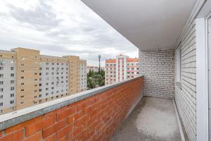 a balcony with a brick wall and buildings at Просторная квартира со свежим ремонтом in Pavlodar