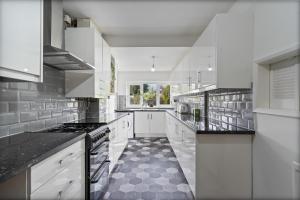 eine Küche mit weißen Schränken und schwarzen Arbeitsplatten in der Unterkunft Luxury Birmingham Solihull Spacious Home - Driveway - Groups of 8 Max - 3 Bedrooms 4 or 6 Beds Fully Equipped Home - Near City Centre NEC HS2 Sites Edgbaston Moseley& lots more! in Birmingham