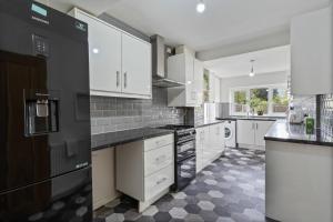 eine Küche mit weißen Schränken und einem schwarzen Kühlschrank in der Unterkunft Luxury Birmingham Solihull Spacious Home - Driveway - Groups of 8 Max - 3 Bedrooms 4 or 6 Beds Fully Equipped Home - Near City Centre NEC HS2 Sites Edgbaston Moseley& lots more! in Birmingham + 51 Fotos