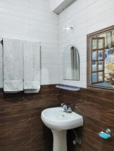 a bathroom with a sink and a mirror and towels at Verma Guest House in Dharmsala