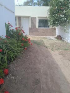 eine Auffahrt, die zu einem Haus mit roten Blumen führt in der Unterkunft Alojamiento Rivadavia in General Villegas