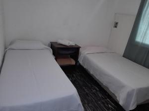 Zimmer mit 2 Betten und einem Tisch mit Telefon in der Unterkunft Alojamiento Rivadavia in General Villegas