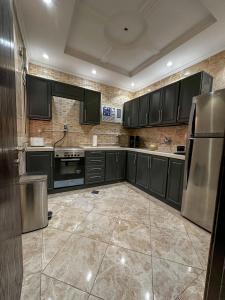 a kitchen with black cabinets and stainless steel appliances at Cozy 2-Bedroom Apartment in Batha Quraish in Makkah
