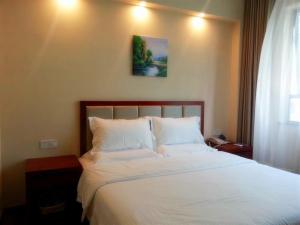 a bedroom with a bed with white sheets and a picture on the wall at GreenTree Inn ShangHai SongJiang SongDong Business Hotel in Songjiang