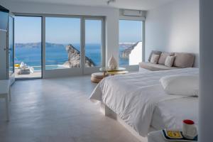 a white bed sitting in front of a large window at Keti Hotel in Fira