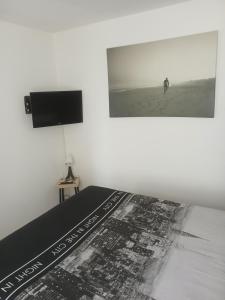 Un dormitorio con una cama con un cuadro en la pared. en appartement résidentiel 2 pièces, en Pierrefitte-sur-Seine