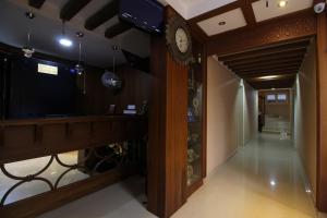 a hallway with a clock on the wall and a hallway with a room with at Srivar Hotels in Guruvāyūr