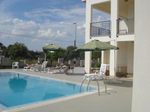 ein Pool mit Liegestühlen und Sonnenschirmen neben einem Gebäude in der Unterkunft Lina apartments A1 in Ginosa Marina