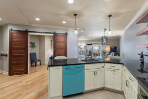 a kitchen with white cabinets and a blue dishwasher at Grand Theatre Condo in the Heart of Downtown Grand Haven in Grand Haven