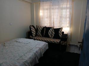a bedroom with a bed and a couch in front of a window at Airbnb in Mwea town in Thiba