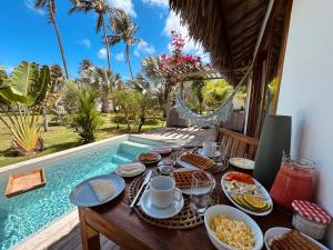 a table with food on it next to a swimming pool at Tiki Pool's Bungalows in Fortim