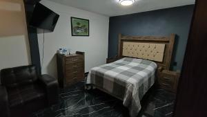 a bedroom with a bed and a chair and a television at Casa Mi viejo San Juan in San Juan Teotihuacán