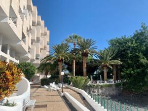 a resort with palm trees and chairs and a building at Urbanización Playa Chica in Santa Cruz de Tenerife