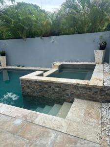 a swimming pool in front of a white wall at hermosa casa en las orquídeas la romana in La Romana