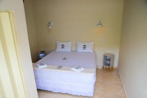 a bedroom with a white bed with two pillows at Pousada Mama África in Conservatória
