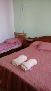two white towels are laying on a pink bed at la casa de la abuela in San Pedro