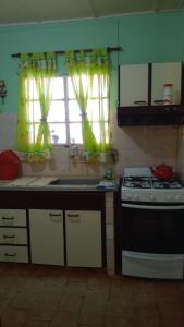 a kitchen with a stove and a window with curtains at la casa de la abuela in San Pedro +5 photos