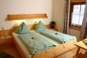 a bedroom with a wooden bed with green pillows at Berggasthof-Ferienbauernhof Habersatt in Altenmarkt im Pongau