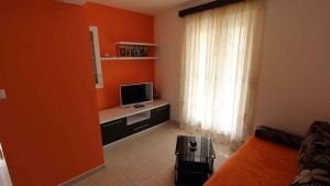 salon z pomarańczową ścianą i telewizorem w obiekcie Malinska Apartment 2 w mieście Sveti Anton