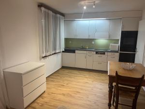kuchnia z białymi szafkami i stołem oraz jadalnia w obiekcie Studio 5 Minuten von Murten w mieście Münchenwiler