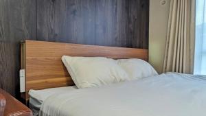un lit avec une tête de lit en bois et des oreillers blancs dans l'établissement Yonagunijima Hotel Munbu Stay Kukomae - Vacation STAY 87378v, à Sonai