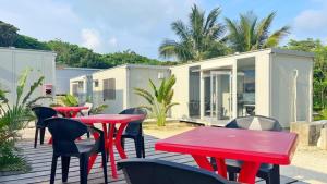 une terrasse avec des tables et des chaises rouges et une maison dans l'établissement Yonagunijima Hotel Munbu Stay Kukomae - Vacation STAY 87378v, à Sonai
