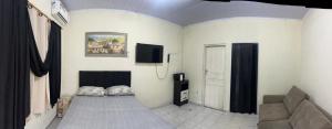 a living room with a couch and a tv on the wall at Kitnets da Lu in Ubatuba