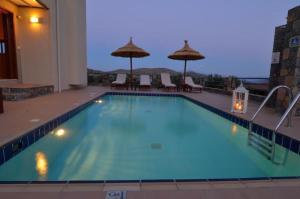 a large swimming pool with chairs and umbrellas at Elounda Blue Island Villa in Elounda