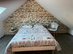 a bedroom with a bed with a brick wall at Maison cosy du Bocage Ornais in Condé-sur-Sarthe