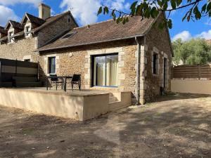 a house with a patio with a table in front of it at Maison cosy du Bocage Ornais in Condé-sur-Sarthe