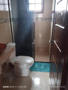 ein Badezimmer mit Toilette und Glasdusche in der Unterkunft Casa com piscina Barê in São Sebastião
