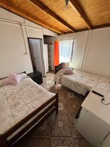 een kamer met twee bedden en een tafel erin bij Hospedaje Pensión Ely Habitación doble in Temuco