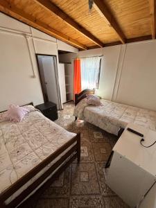 een kamer met twee bedden en een tafel erin bij Hospedaje Pensión Ely Habitación doble in Temuco