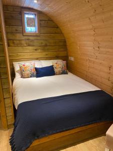 a bed in a room with a wooden wall at Crabmill glamping bewdley in Bewdley