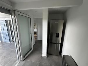 a hallway with a stainless steel refrigerator in a building at L'O - Au cœur de la Grande Terre - T1 in Morne-à-lʼEau