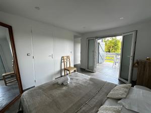 a bedroom with a bed and a chair and a balcony at L'O - Au cœur de la Grande Terre - T1 in Morne-à-lʼEau