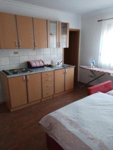 a kitchen with wooden cabinets and a sink and a bed at studio SM IK 3 in Tomislavgrad