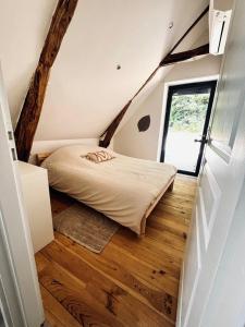 a bedroom with a bed in a attic with a window at La Grange aux Souvenirs - Piscine chauffée ,Jacuzzi et Terrain de pétanque in Grèzes