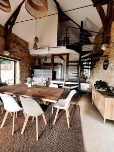 a dining room with a wooden table and chairs at La Grange aux Souvenirs - Piscine chauffée ,Jacuzzi et Terrain de pétanque in Grèzes