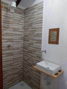 a bathroom with a white sink and a brick wall at Chale proximo a praia in Ilhabela +46 photos