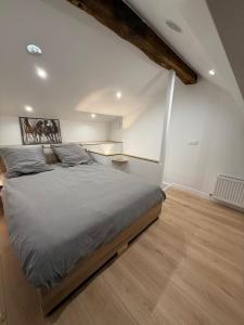 een slaapkamer met een groot bed en een houten vloer bij La Demeure du Chevalier in Saint-Cyr-lʼÉcole