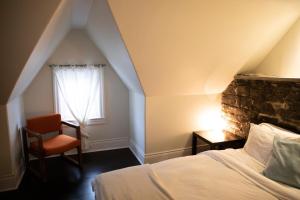 een slaapkamer met een bed, een stoel en een raam bij KingstonStays Spacious Historic Downtown Stableman's House Loft in Kingston