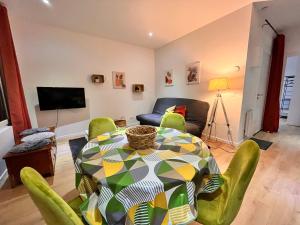 a living room with a table and chairs and a couch at Villa La Butte, Appartements Chaleureux au Cœur de La Bourboule in La Bourboule