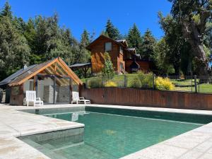 a swimming pool in front of a house at Portal del Manzano in Villa La Angostura