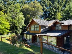 a log home with a metal roof and windows at Portal del Manzano in Villa La Angostura