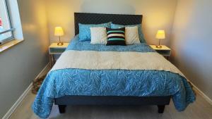 a bedroom with a bed with a blue comforter and two lamps at Depto Playa Pto Montt Pelluco in Puerto Montt