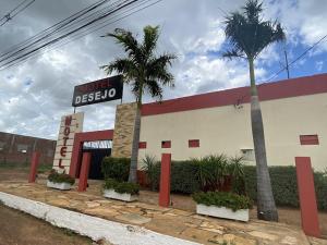 a building with two palm trees in front of it at Motel Desejo Mossoró in Mossoró