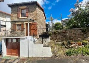 a stone house with a wooden door and a stone wall at Maison Cantalou in Massiac