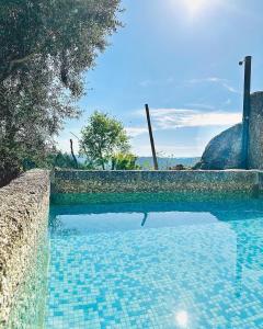 a swimming pool with a blue tile floor and a wall at Pedacinho do Céu in Vieira do Minho